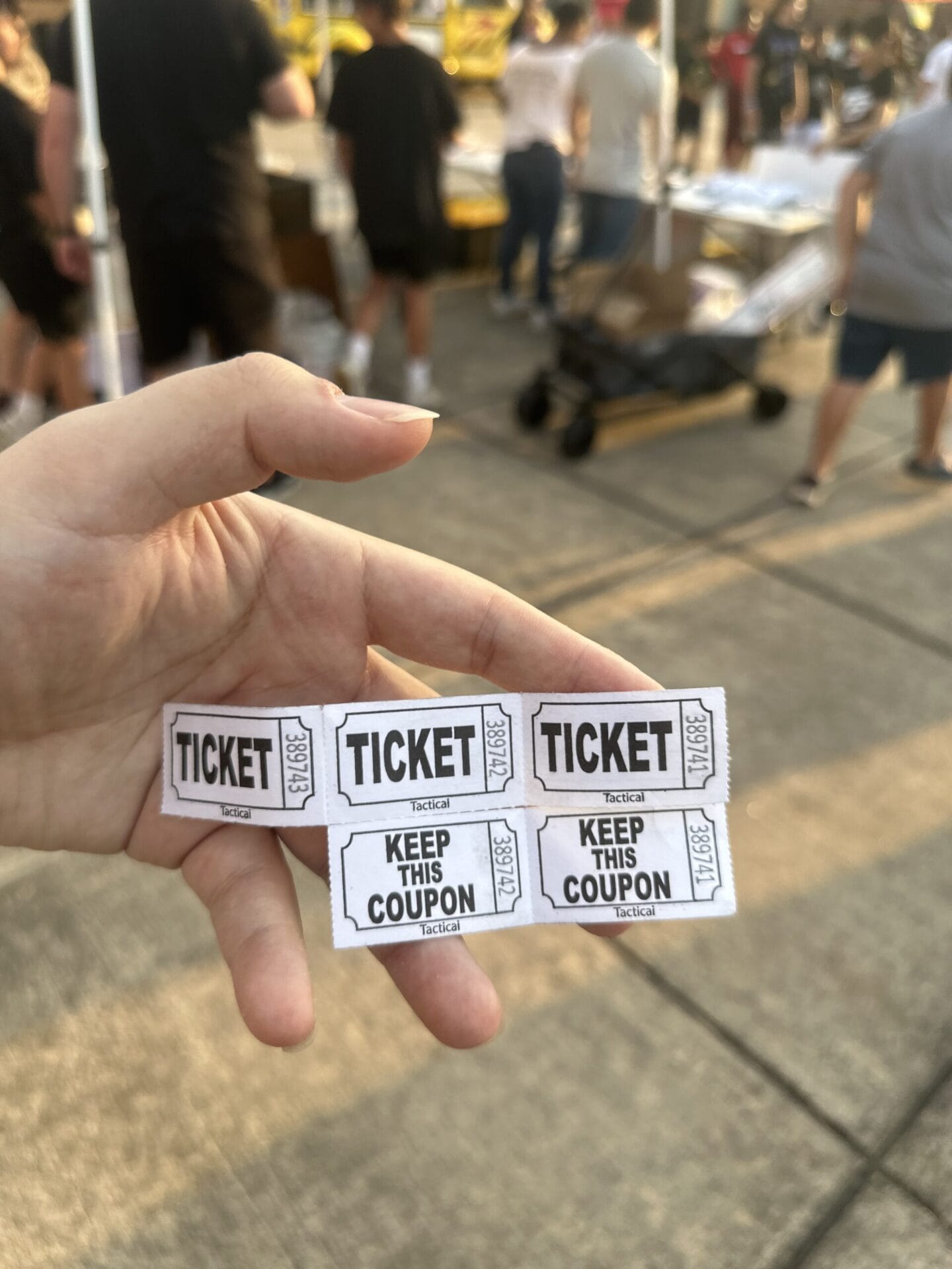 Robert's hand holding physical tickets for a fundraiser raffle.