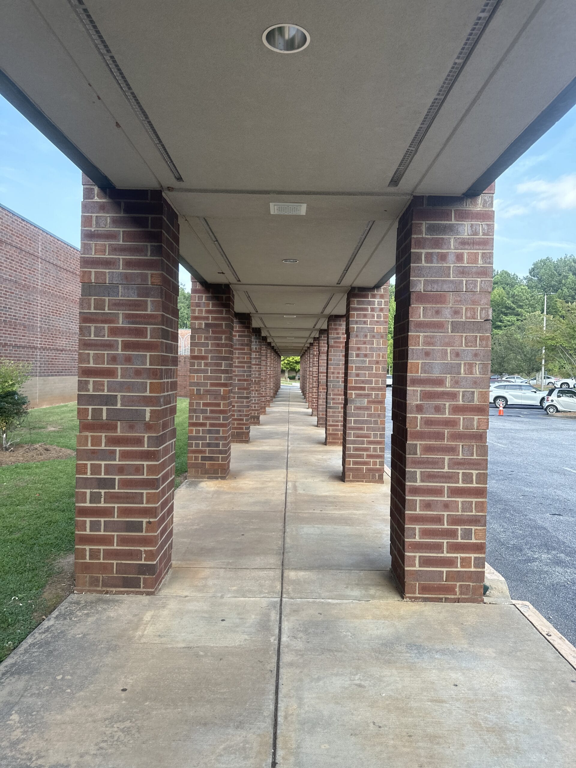 Photo of looking down an outside walk-way with brick pillars.
